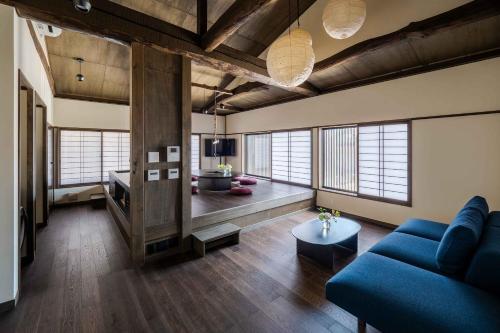 a living room with a blue couch and some windows at Nananohi Machiya House in Takayama