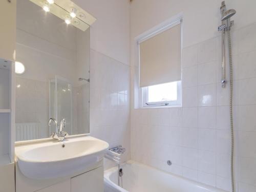 a white bathroom with a sink and a bath tub at Cozy Zeeland Retreat with a Sauna in Wemeldinge