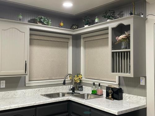 a kitchen with a sink and two windows withvisors at Hugo Cozy Cottage in Hugo