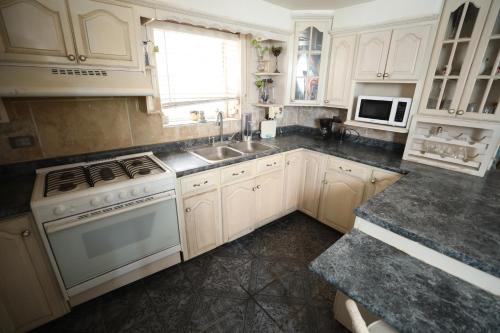 a kitchen with white cabinets and a stove and a sink at Xio's House in Manuel F. Martínez