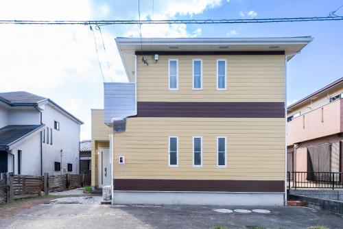 a yellow house with blue windows on the side of it at ジブリパークまで車10分 遊べるキッズハウス1棟貸切り 敷地内無料駐車場あり 最大12名 in Seto