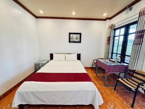 a bedroom with a bed and a chair and windows at Tuan Ngoc Hotel in Ninh Binh