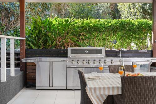 カラウンドラにあるCaloundra Beach Break - 3BD Family Homeのグリルと飲み物のテーブルを備えた屋外キッチン