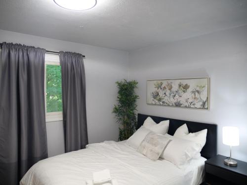 a bedroom with a bed with white sheets and a window at Entire Unique Apartment in Kingston