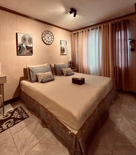 a large bed in a room with a clock on the wall at Lydelles Guesthouse in Butuan