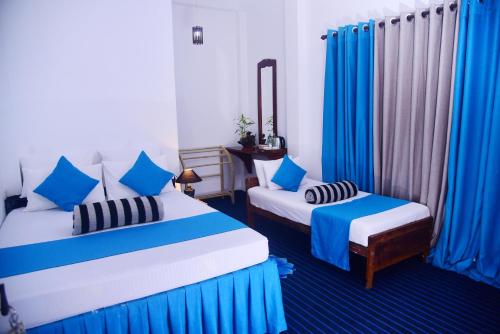 a bedroom with two beds and blue curtains at Travel rest inn in Ella