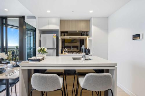 a kitchen with a large island with bar stools at Your QW Escape - Pool Gym & Stunning Sky Deck View in Brisbane