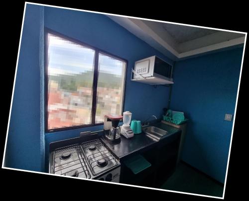 a blue kitchen with a stove and a window at Bello mini Depa DxA - rentaflex com mx in Mexico City