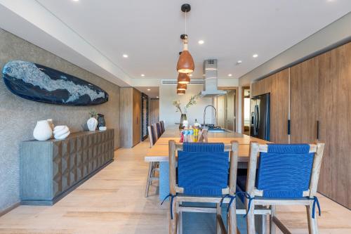 a kitchen and dining room with a table and blue chairs at Punto Nima, Spectacular Pool with Ocean View in San José del Cabo