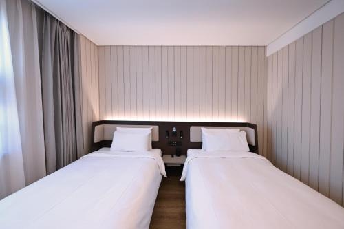 two beds in a small room with white sheets at Hanting Hotel Beijing Garden Expo Park Dujiakan in Beijing