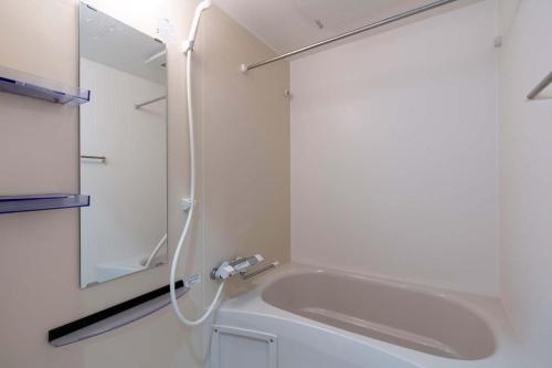 a bathroom with a bath tub and a mirror at Anri Kitazume in Osaka