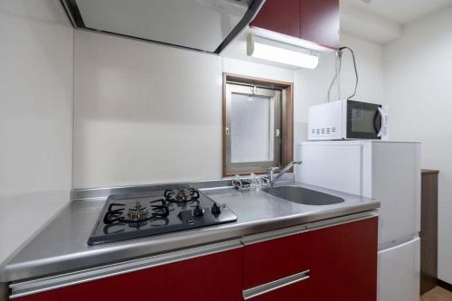 a kitchen with a sink and a stove and a refrigerator at Anri Kitazume in Osaka