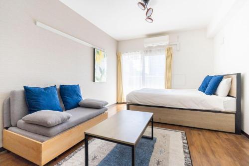 a bedroom with a couch and a bed with blue pillows at Anri Kitazume in Osaka
