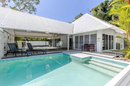 a swimming pool in front of a house at Serenity Villa with heated POOL & Beach access in Port Douglas