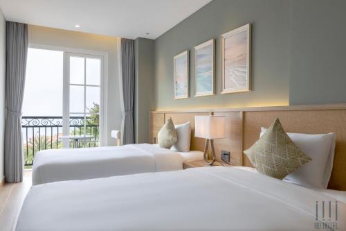 two beds in a hotel room with a window at HD Hotel Sunset Town in Phu Quoc