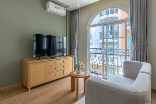 a living room with a tv and a chair and a window at HD Hotel Sunset Town in Phu Quoc