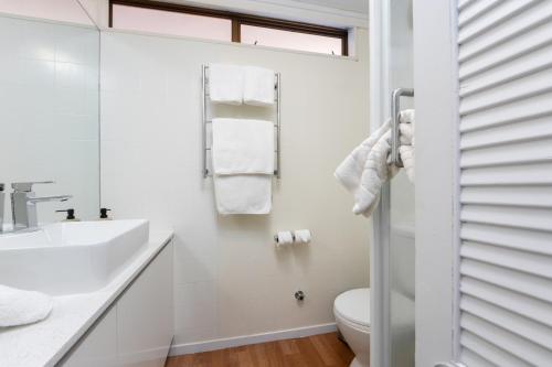a white bathroom with a sink and a toilet at Epsom Motel in Auckland