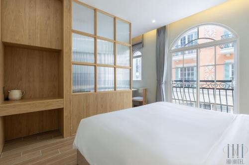 a bedroom with a white bed and a window at HD Hotel Sunset Town in Phu Quoc
