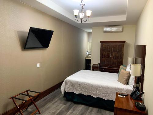 a bedroom with a bed and a tv on the wall at Hotel Hacienda Santana in Tecate