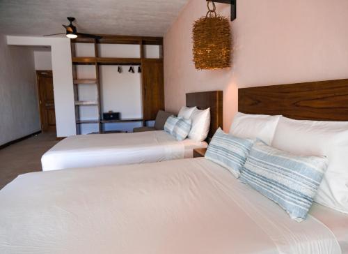 two beds in a hotel room with white sheets at The Mint Resort Isla Mujeres in Isla Mujeres