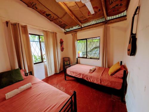 a bedroom with two beds and two windows at Don Jiménez Guesthouse in Puerto Jiménez