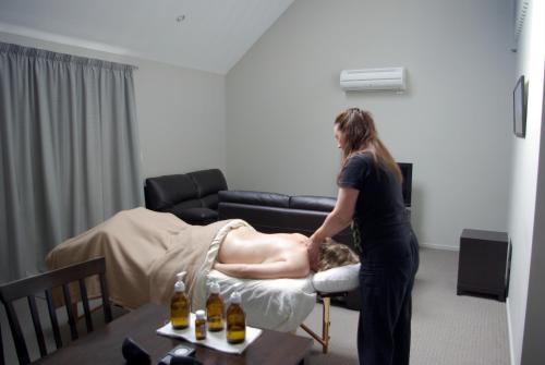 a woman giving a man a massage in a room at Hanmer Apartments in Hanmer Springs
