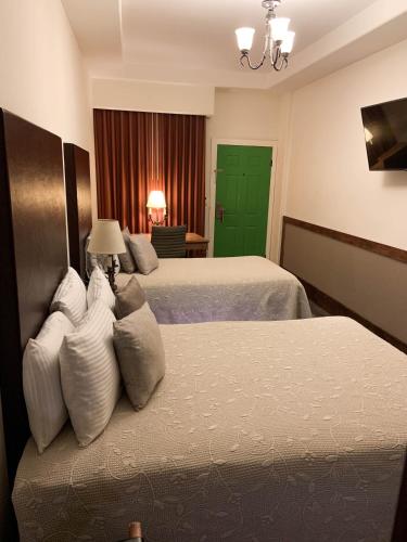 a hotel room with two beds and a green door at Hotel Hacienda Santana in Tecate