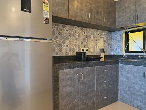 una cucina con mobili grigi e piastrelle blu di Forest Frame - Kudrat Nilaya Valley View with pool a Canacona
