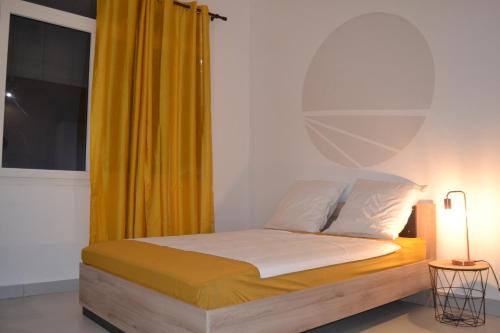 a bedroom with a bed with a yellow curtain at Galhy's House in Saint-Claude