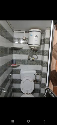 a bathroom with a toilet and a bucket on the wall at KHS ROOMs near ghat and temples in Varanasi