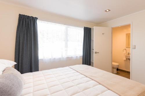 a bedroom with a bed and a large window at Seabeds in Paihia