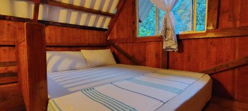 a bed in a wooden room with a window at Sapiens house la cabaña del Reloj in Cali
