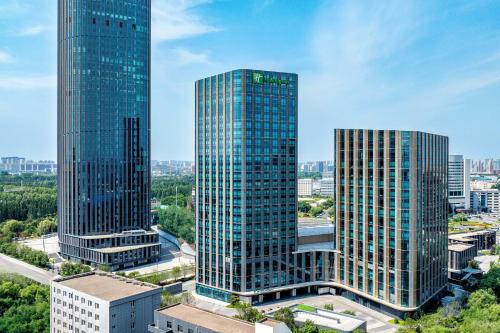two tall skyscrapers in a city with trees at Holiday Inn Changchun High Tech Zone by IHG in Changchun