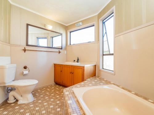 a bathroom with a tub and a toilet and a sink at Beachfront Landing - Pauanui Holiday Home in Pauanui