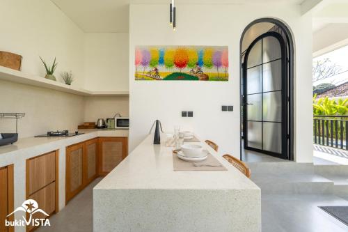 a kitchen with a table and a painting on the wall at Kahuna Villas by Bukit Vista in Sanur