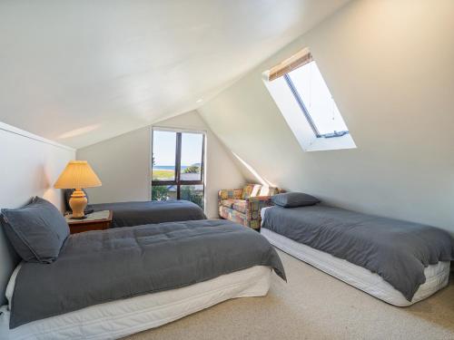 a attic bedroom with two beds and a window at Beachfront Landing - Pauanui Holiday Home in Pauanui