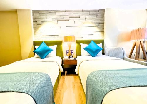 two beds in a hotel room with blue pillows at Cyberview Resort & Spa in Cyberjaya