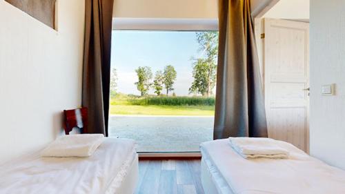 two beds in a room with a large window at Vana-Piiri Puhkemaja in Kodukula