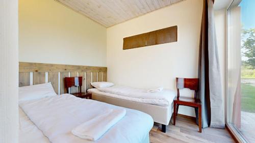 a bedroom with two beds and two chairs and a window at Vana-Piiri Puhkemaja in Kodukula