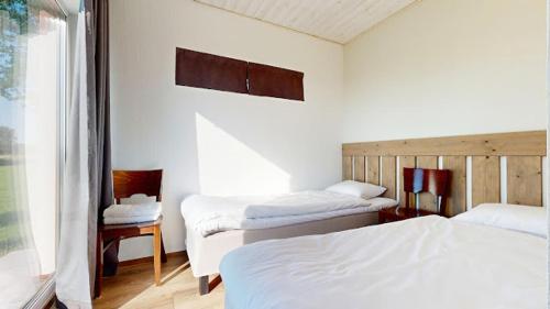 a bedroom with two beds and two chairs and a window at Vana-Piiri Puhkemaja in Kodukula