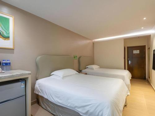 two beds in a hotel room with a sink at Leisurely Hotel Shenzhen in Shenzhen