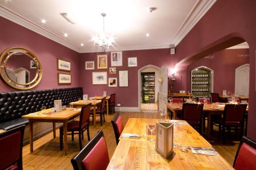 a restaurant with wooden tables and chairs and purple walls at The Corner House Hotel in Taunton