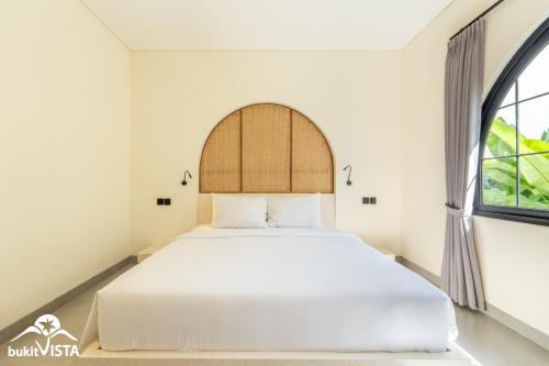 a bedroom with a white bed and a window at Kahuna Villas by Bukit Vista in Sanur