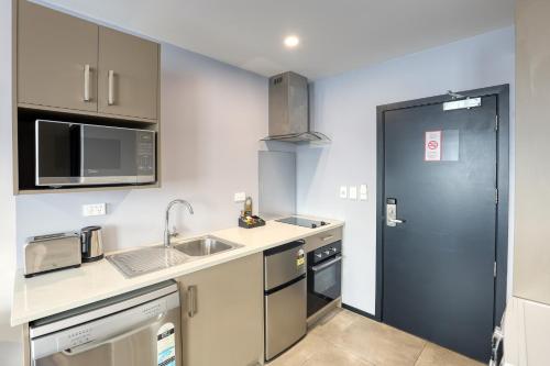 a small kitchen with a sink and a microwave at Marsden Suites Albany in Albany