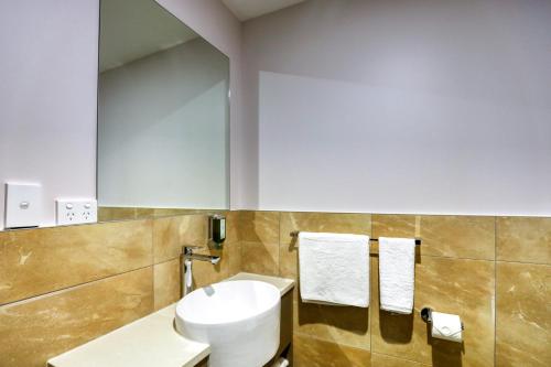 a bathroom with a white toilet and a mirror at Marsden Suites Albany in Albany