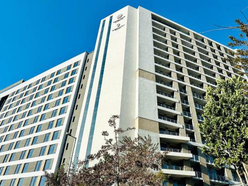 a tall white building with trees in front of it at Menlyn Maine Residences - Superior king - Paris apartment in Pretoria