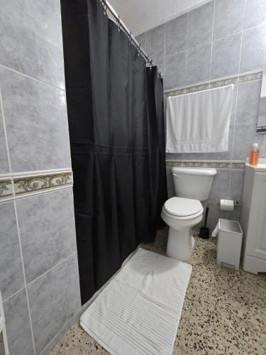a bathroom with a toilet and a black shower curtain at Casa Los Tercoz in Luquillo