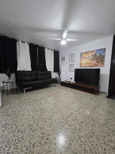 a living room with a couch and a flat screen tv at Casa Los Tercoz in Luquillo