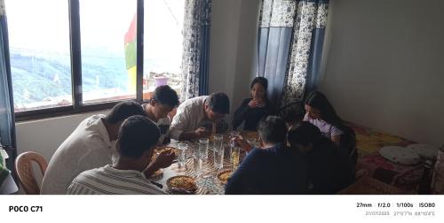 a group of people sitting around a table eating food at Mane Dara homestay in Darjeeling
