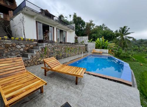 a pool with two benches and a house at Nona Lodge in Tetebatu